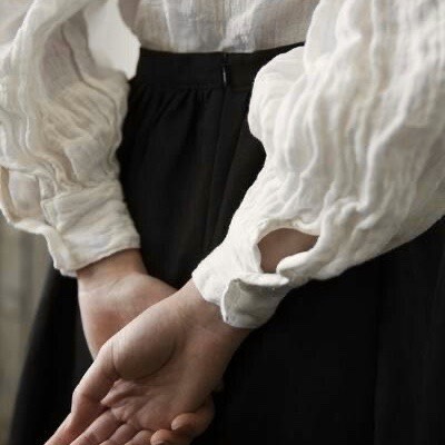Closeup photo of hands held behind the back, dressed in poofy white sleeves