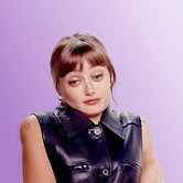 Ella Purnell in a leather vest shrugging nonchalantly